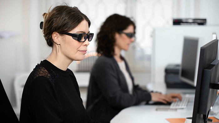 Två kvinnor med brusreducerande glasögon i kontorsmiljö